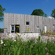 Das Besucherzentrum Marienmünster mit moderner Holzfassade, umgeben von bunten Wildblumen.