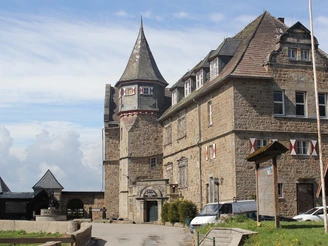 Burg Schwalenberg Burg Schwalenberg aus Stein mit markantem Turm und Fachwerk-Elementen, umgeben von Wolken.