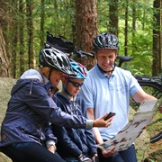 Radler am Steingräberfeld Giersfeld in Ankum Familie mit Fahrradhelmen beim Kartenlesen auf einem Felsen im Wald.