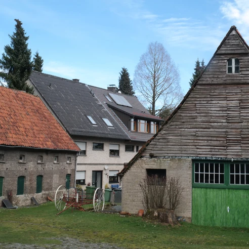 Unterwegs auf dem TERRA.track Zittertal Historische Bauernhäuser mit markanten Holzdächern und grünen Türen vor einer malerischen Kulisse.