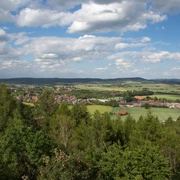 Weitblicke Landschaft von Wäldern und Feldern in sanften Hügeln unter blauem Himmel mit weißen Wolken.