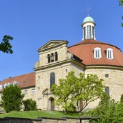 Kloster Ohrbeck Kirche mit oktogonalem Turm, blauer Kuppel und Steinmauer an sonnigem, klaren Tag.
