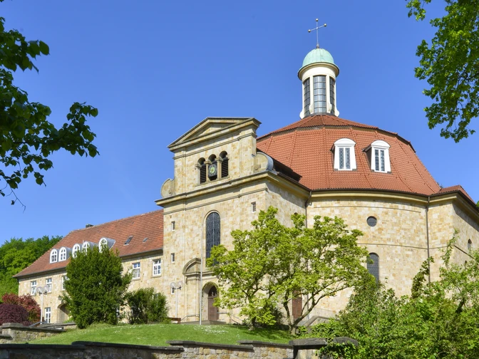 Kloster Ohrbeck Kirche mit oktogonalem Turm, blauer Kuppel und Steinmauer an sonnigem, klaren Tag.