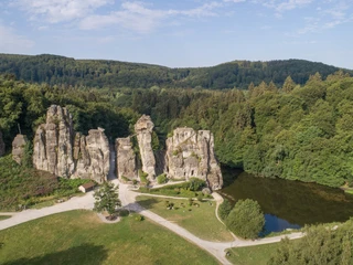 Externsteine Naturlandschaft mit beeindruckenden Sandsteinfelsen, umgeben von dichtem Wald und einem kleinen Teich.
