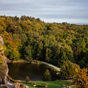 Ausblick Externsteine Blick auf die majestätischen Externsteine mit üppig grünem Wald und einem kleinen See im Vordergrund.