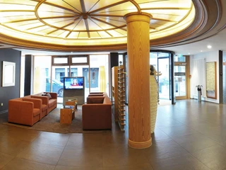 hotel-niedersachsen-foyerundrezeption Foyer eines Hotels mit moderner Rezeption, bequemen Sitzbereichen und großzügiger Beleuchtung.