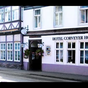 Fachwerkhaus mit Schild "Hotel Corveyer Hof" an der Fassade, Fenster mit Blumenkästen dekoriert.