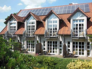 Hotel Hubertushof Das Bild zeigt ein zweistöckiges Gebäude mit Ziegeldach und weißen Fensterfronten in grüner Umgebung.
