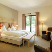 Zimmer im Landgasthof Mücke in Marsberg Geräumiges Landgasthof-Zimmer mit Doppelbett, Schreibtisch, Sesseln und einem großen Fenster mit Blick ins Grüne.