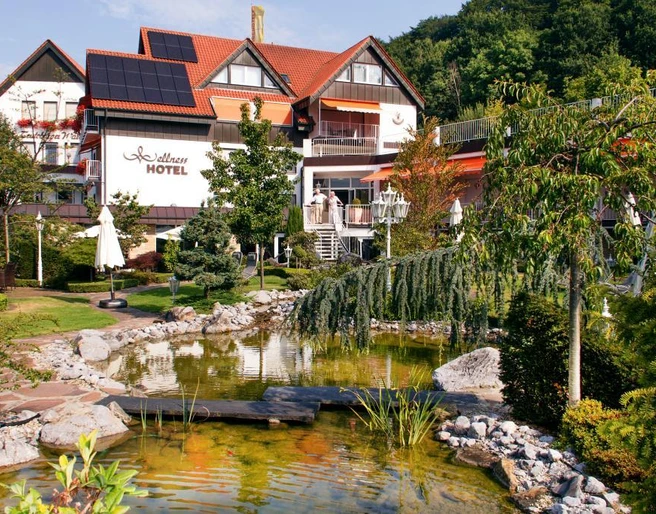 Ringhotel Teutoburger Wald****, Tecklenburg Brochterbeck Ringhotel Teutoburger Wald: Ein gepflegter Garten mit Teich und Brücke vor einem Hotelgebäude.