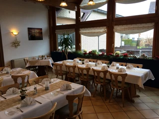 Gasthaus Engemann, Gaststube Gasthaus Engemann Gaststube mit Holzmöbeln, gedeckten Tischen, großen Fenstern und Pflanzen.