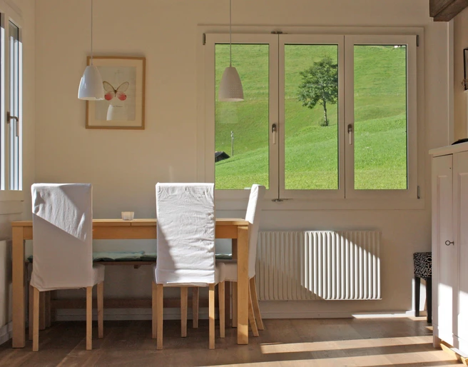 Salle à manger de l'appartement de vacances Hölzerner Esstisch mit weissen StühlenWooden dining table with white chairsTable de salle à manger en bois avec chaises blanches