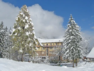 Exterior view of Hotel Kurhaus Grimmialp in winter Verschneites Hotelgebäude aus der Belle EpoqueSnow-covered hotel building from the Belle EpoqueBâtiment d'hôtel enneigé de la Belle Époque