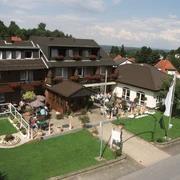 aussenansicht_haus-weber Zweistöckiges Gästehaus mit Blumenbalkonen und Terrasse, umgeben von gepflegtem Garten, Voralpen.