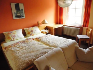 cimg0181 Ein lichtdurchflutetes Doppelzimmer mit zwei Betten, Schreibtisch und gemütlichem Sofa.