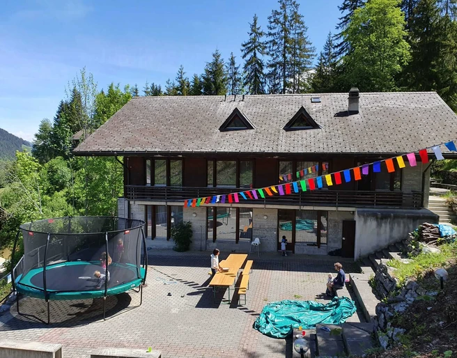 Aussenansicht Ferienhaus Edelweiss Hölzernes Gruppenhaus von Aussen, davor hängt eine TibetfahneWooden group house from the outside, with a Tibetan flag hanging in front of itMaison de groupe en bois vue de l'extérieur, devant laquelle est accroché un drapeau tibétain