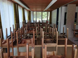 Der grosse Essraum des Gruppenhauses Essraum mit Tischen und hochgestellten dunkelbraunen StühlenDining room with tables and high dark brown chairsSalle à manger avec tables et chaises marron foncé placées en hauteur