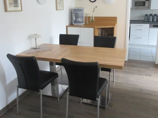 Moderner Essbereich mit Holz-Esstisch und vier schwarzen Stühlen, harmonisch kombiniert mit Küche.