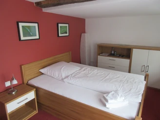 Ein helles Einzelzimmer mit Holzdekor, roter Wand und minimalistischer Einrichtung für Gäste.