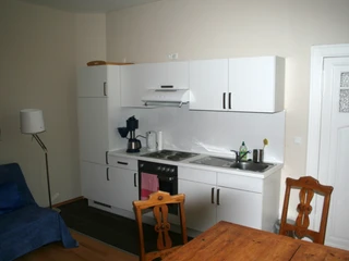 Riederhof 26 Moderne Küchenzeile mit Herd, Dunstabzugshaube, Spüle und weißer Möblierung in wohnlichem Ambiente.