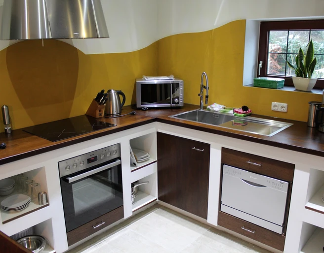 Soulplace Boardinghouse Eine moderne Küche mit Holzarbeitsplatte, ausgestattet mit Herd, Mikrowelle und Spülmaschine.