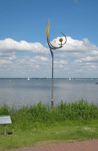 "Tanz der Winde" von Jörg Wiele  Metallskulptur von Jörg Wiele am Steinhuder Meer, mit Segelbooten und Wolkenhimmel im Hintergrund.