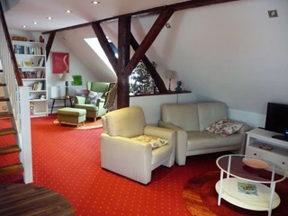 fewo-kuenstlerhauspotthast-spitzboden-wohnbereich Wohnbereich mit Ledersofa und Lesesessel im Hintergrund