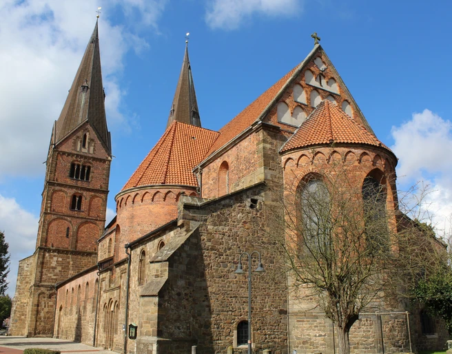 Stiftskirche Bücken: Historische Kirche aus rotem Backstein mit markanten Türmen unter blauem Himmel.