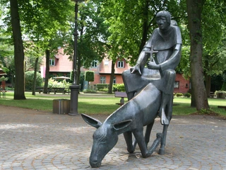 Bronzeskulptur in einem Park, zeigt einen Mönch auf einem Esel, inspiriert von der Gründungslegende.