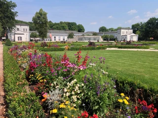 Barockgarten mit Blick auf "Brunnentheater" und Schlosshalle Blumenbeete vor dem barocken Brunnentheater und der Schlosshalle, eingebettet in eine gepflegte Gartenanlage.