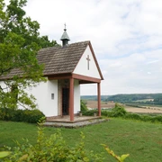 Heimkehrerkapelle Istrup Die Heimkehrerkapelle Istrup steht auf einer grünen Wiese mit Blick auf das hügelige Umland.
