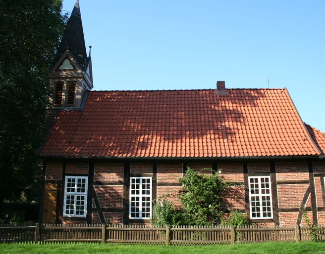 Fachwerkkapelle Anderten Historisches Fachwerkgebäude mit Glockenturm, roten Dachziegeln und weißen Sprossenfenstern.