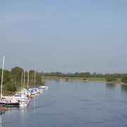 Bootsportverein Achim-Thedinghausen Boote ankern entlang eines grünen Flussufers bei klaren Himmel, perfekt für Wassersportfreunde.