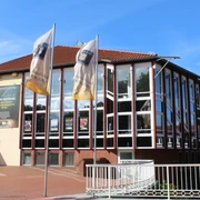 Theater auf dem Hornwerk Nienburg Kulturzentrum mit markanten Glasfassaden und Wimpel vorm Haupteingang, blauer Himmel im Hintergrund.