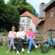 Kloster Schinna Drei Personen entspannen auf einer Bank vor dem historischen Kloster Schinna, umgeben von Fahrrädern.