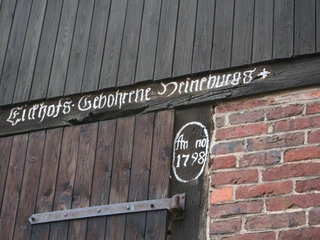 Scheunenviertel Schlüsselburg Holzscheunentor mit schwarz gestrichenen Brettern und handgemalter Inschrift "1798" in weißer Farbe.