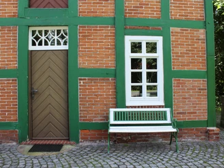 Spieker Lahausen Historisches Backsteingebäude mit grünen Holzbalken und Bank daneben, umgeben von Natur.