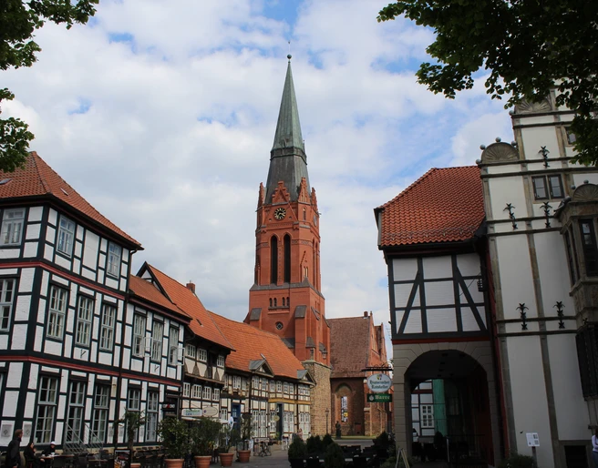 Pfarrkirche St. Martin in Nienburg umgeben von Fachwerkbauten, unter bewölktem Himmel.