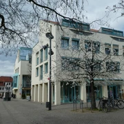 Moderne Architektur des Rathauses Achim mit blühendem Baum im Vordergrund und offener Platzfläche.