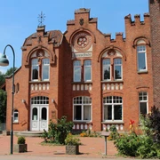 Bauschule Rehburg Backstein-Gebäude der Bauschule Rehburg mit imposanter Fassade und verzierten Fensterbögen bei Sonnenschein.