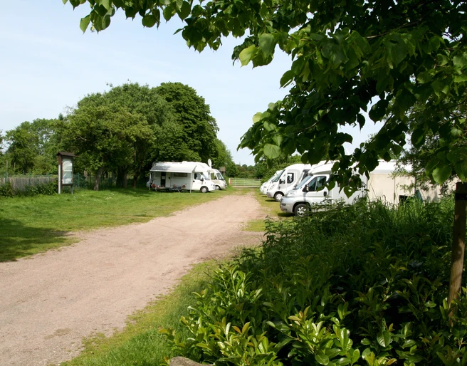 Wohnmobilstellplatz am Schloss Erbhof Wohnmobilstellplatz am Schloss Erbhof im Grünen, mit mehreren geparkten Wohnmobilen und Bäumen.