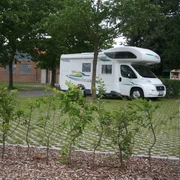 Reisemobilstellplatz Rodewald Ein Reisemobil steht auf einem Stellplatz mit Rasengittern, umgeben von Bäumen und einer Stromsäule.