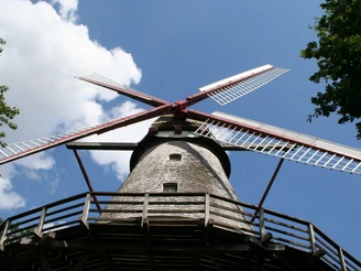 Mühle Eystrup Historische Windmühle mit rot-weißen Flügeln und Holzverkleidung vor blauem Himmel mit Wolken.