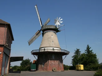 Windmühle Dörverden Historische Windmühle in Dörverden, Backsteinbau, blauem Himmel und umliegenden Gebäuden.
