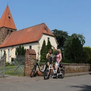 Kirche Eystrup Zwei Fahrradfahrerinnen im Gespräch vor der historischen Kirche Eystrup mit markantem Turm.