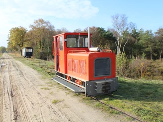 Die Moorbahn Uchte fährt auf schmalen Gleisen durch eine herbstliche Moorlandschaft unter blauem Himmel.