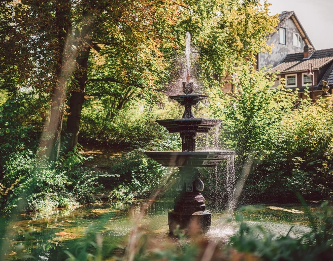 1Brunnen im Stiftsgarten Ein großer Springbrunnen im Einbecker Stiftsgarten im Sommer.