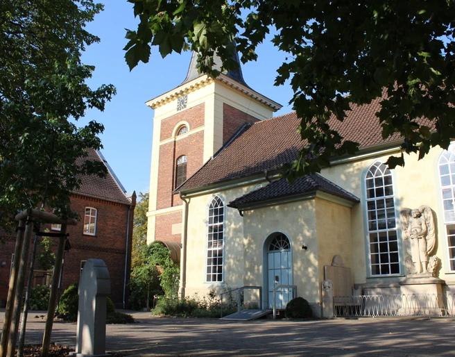 Kirche Uchte Eine historische Kirche mit gelber Fassade, großem Turm und mehreren Rundbogenfenstern.