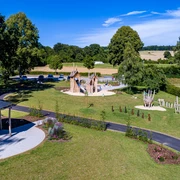Spielplatz im Ludowinengarten Bökendorf, umgeben von grüner Landschaft und blühenden Beeten.