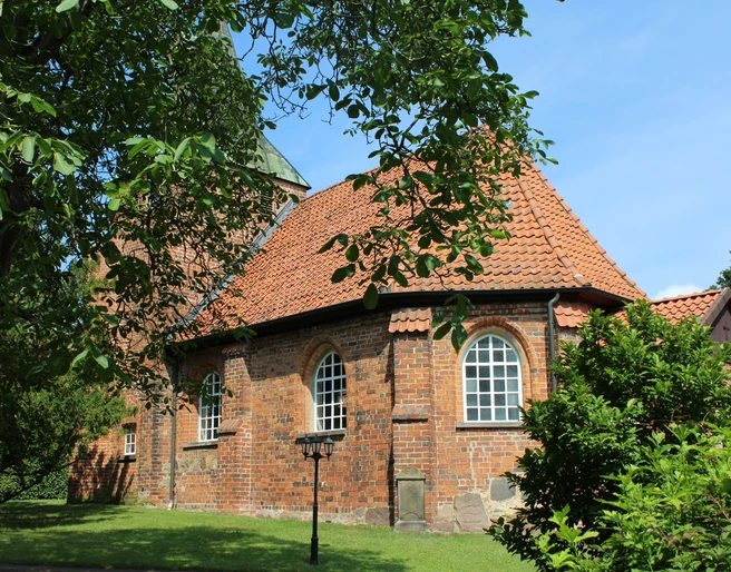 Kirche Binnen Rundziegelbau der Kirche Binnen mit rotem Dach vor einem strahlend blauen Himmel und umgeben von Bäumen.